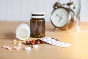 medicine scattered across table with alarm clock in the background